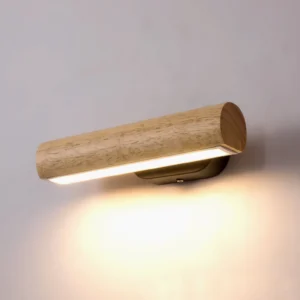 Horizontal wooden LED wall lamp with black metal base emitting warm ambient light, front close-up against gray wall