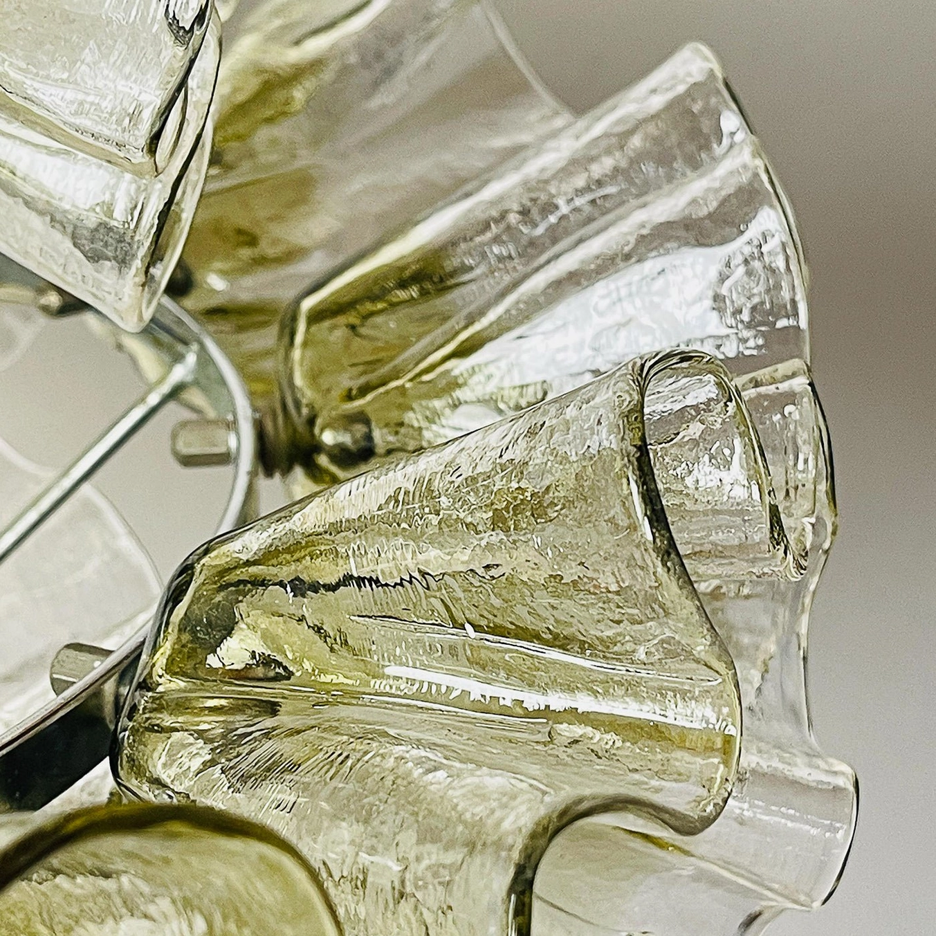 Macro close-up of ruffled glass chandelier showing textured rippled surface and amber-tinted glass with chrome hardware