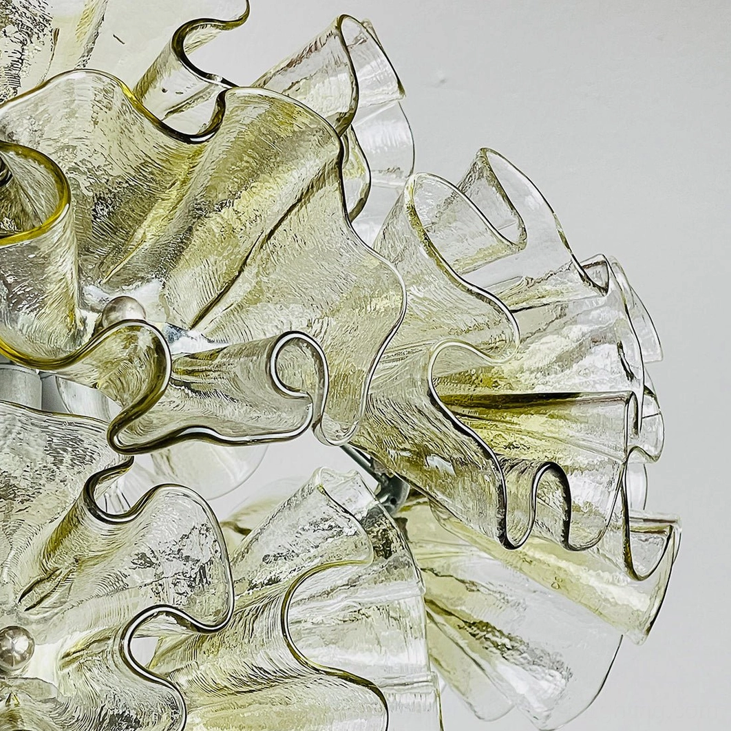 Macro detail of wavy curved glass edges of ruffled petal chandelier highlighting textured amber-tinted hand-blown glass