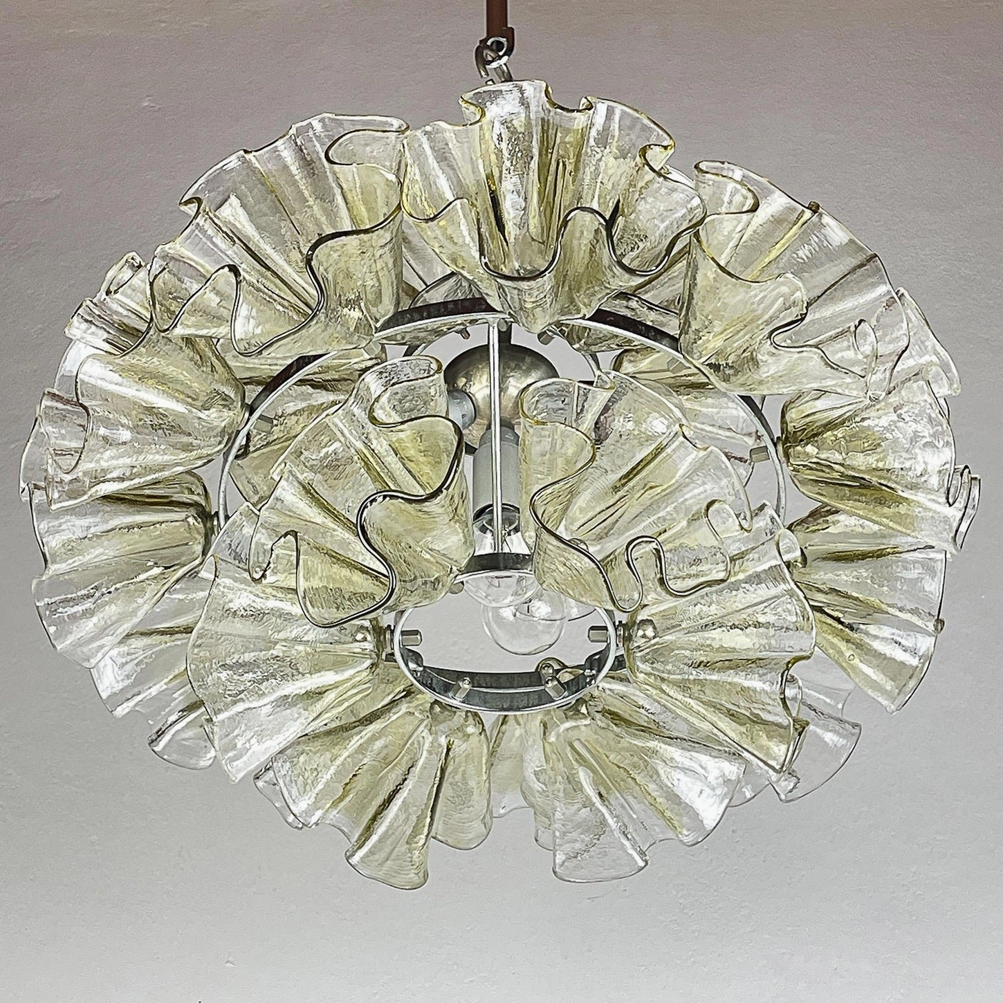 Overhead view of ruffled petal glass chandelier showing symmetrical layered petals, exposed bulb socket, and chrome frame