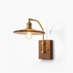 Runia mid-century wall sconce with walnut wood base and brass arm, front oblique view on minimalist white backdrop