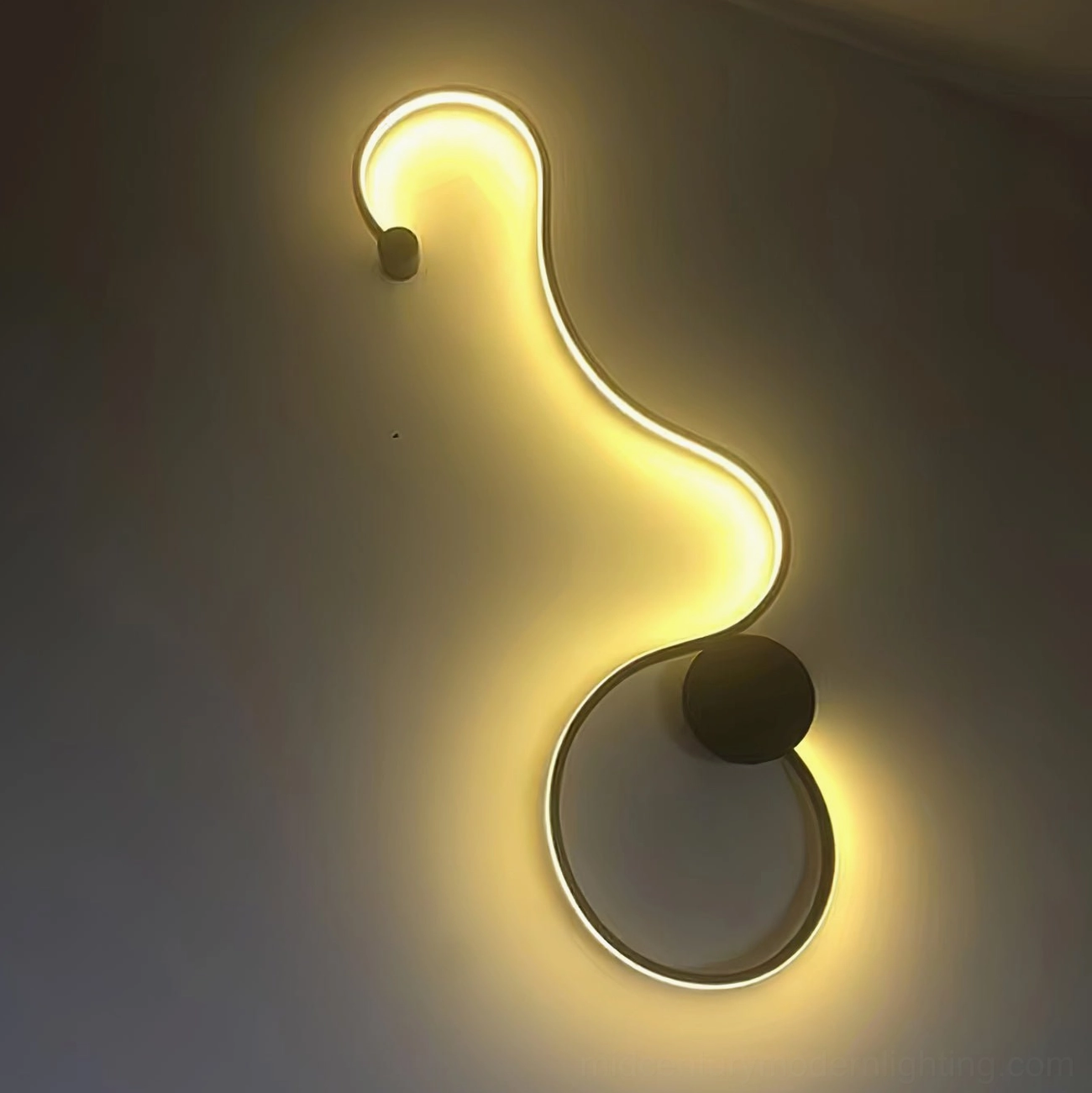 S-shaped snake wall sconce close-up detail on dark gray wall with warm yellow ambient light