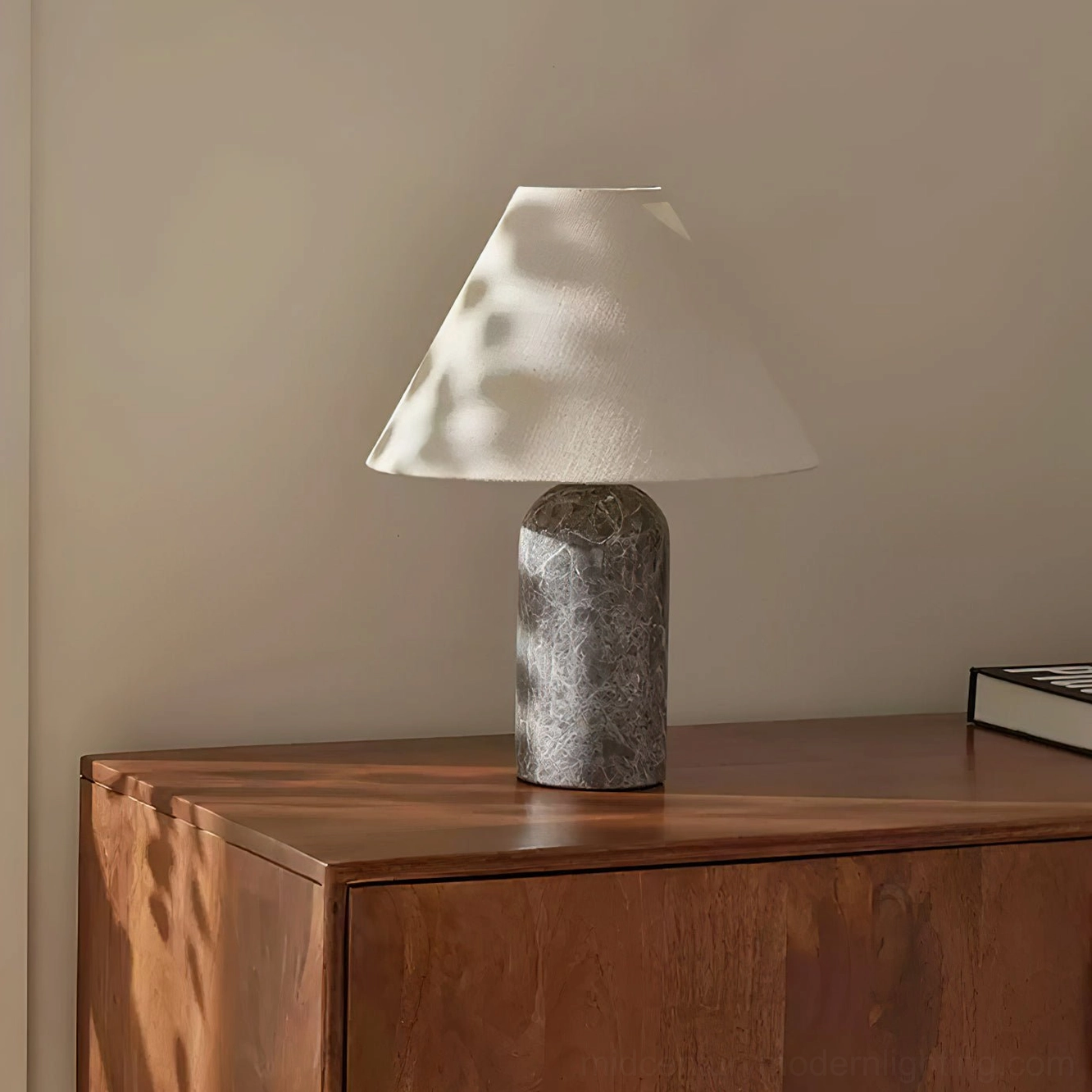 Grey marble table lamp with natural veining on sunny bedroom dresser, warm ambient lighting, three-quarter side view showing conical linen shade