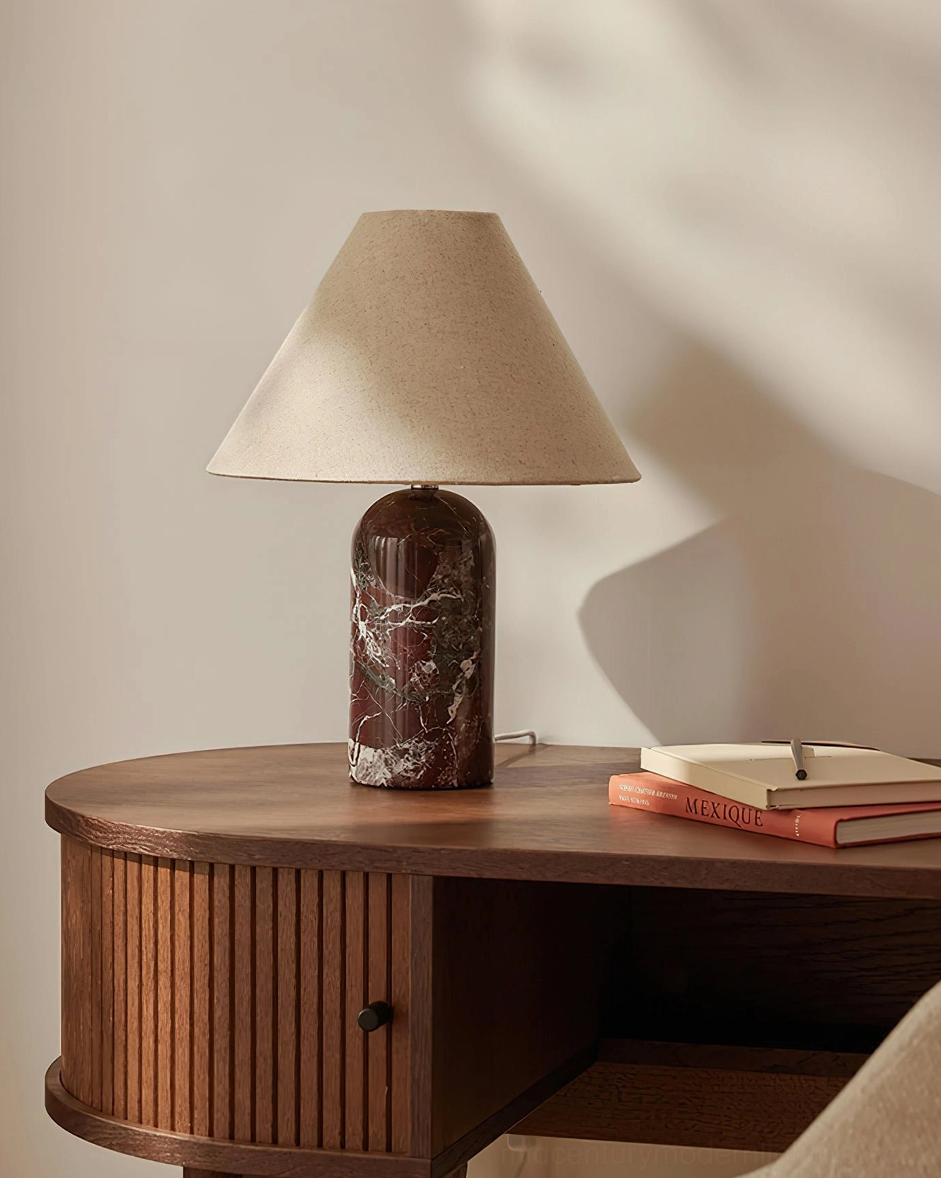 Reddish-brown marble cylinder table lamp on wooden desk in home office study setup, light beige tapered shade, focused task lighting