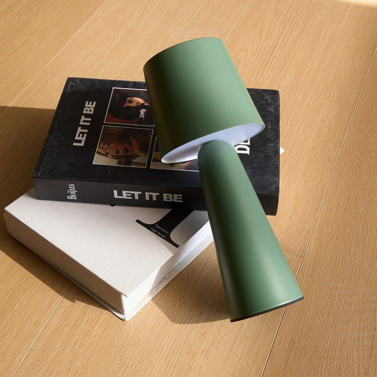 Sage green matte table lamp tilted display overhead view on wooden table with design books