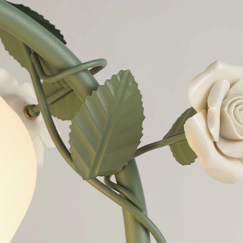 Detailed view of sage green metal frame with white ceramic rose decorations and botanical leaf accents