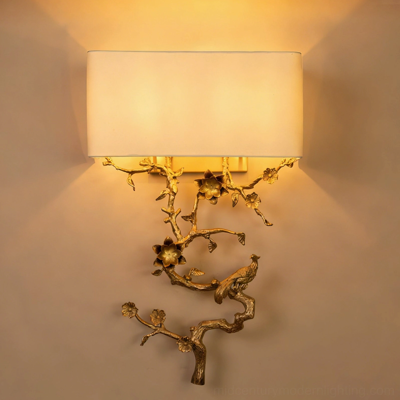 Sanremo wall sconce illuminated on residential wall creating warm ambient light through fabric shade, ornate brass base with botanical bird motif