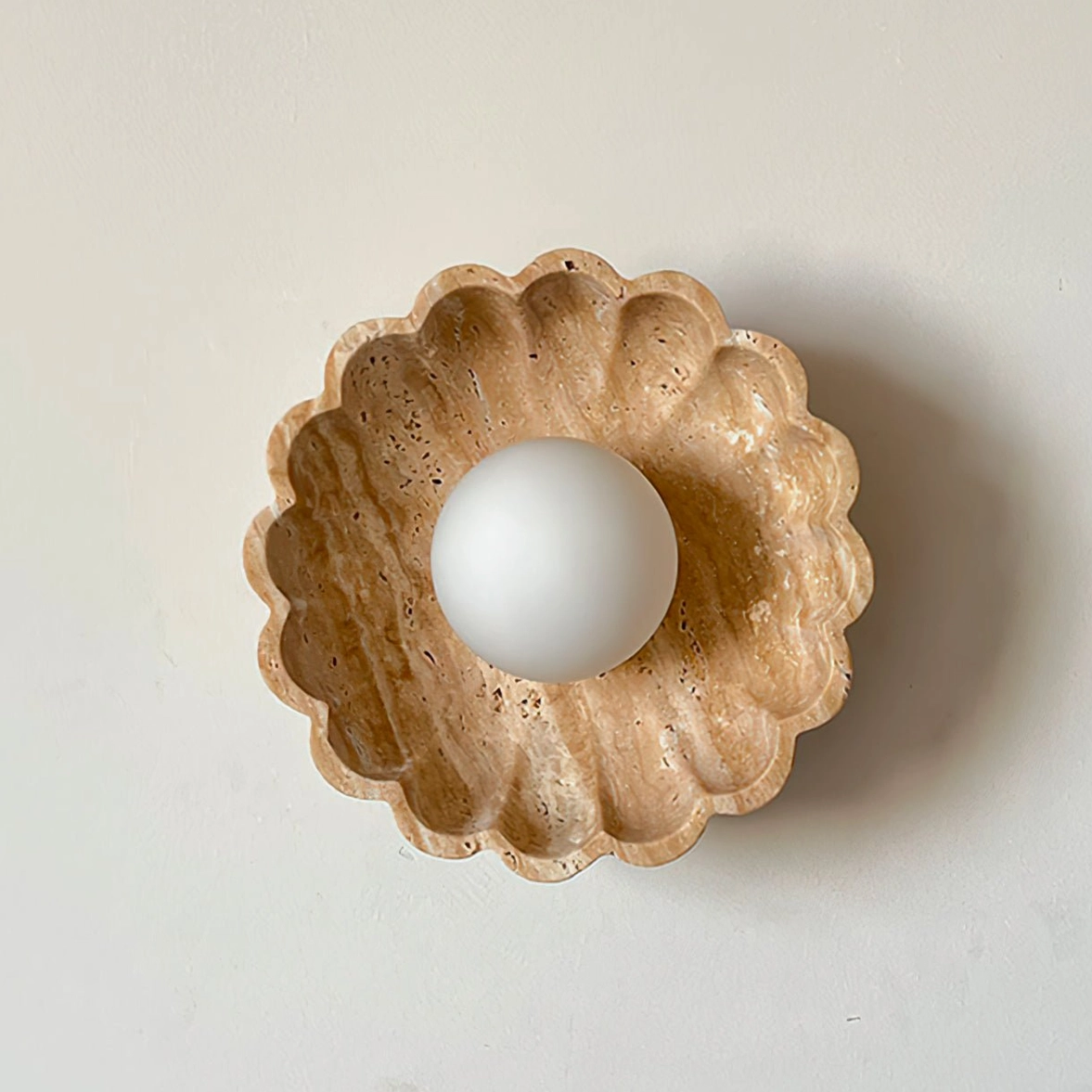 Scallop wall lamp with shell-shaped fluted travertine frame on neutral wall background