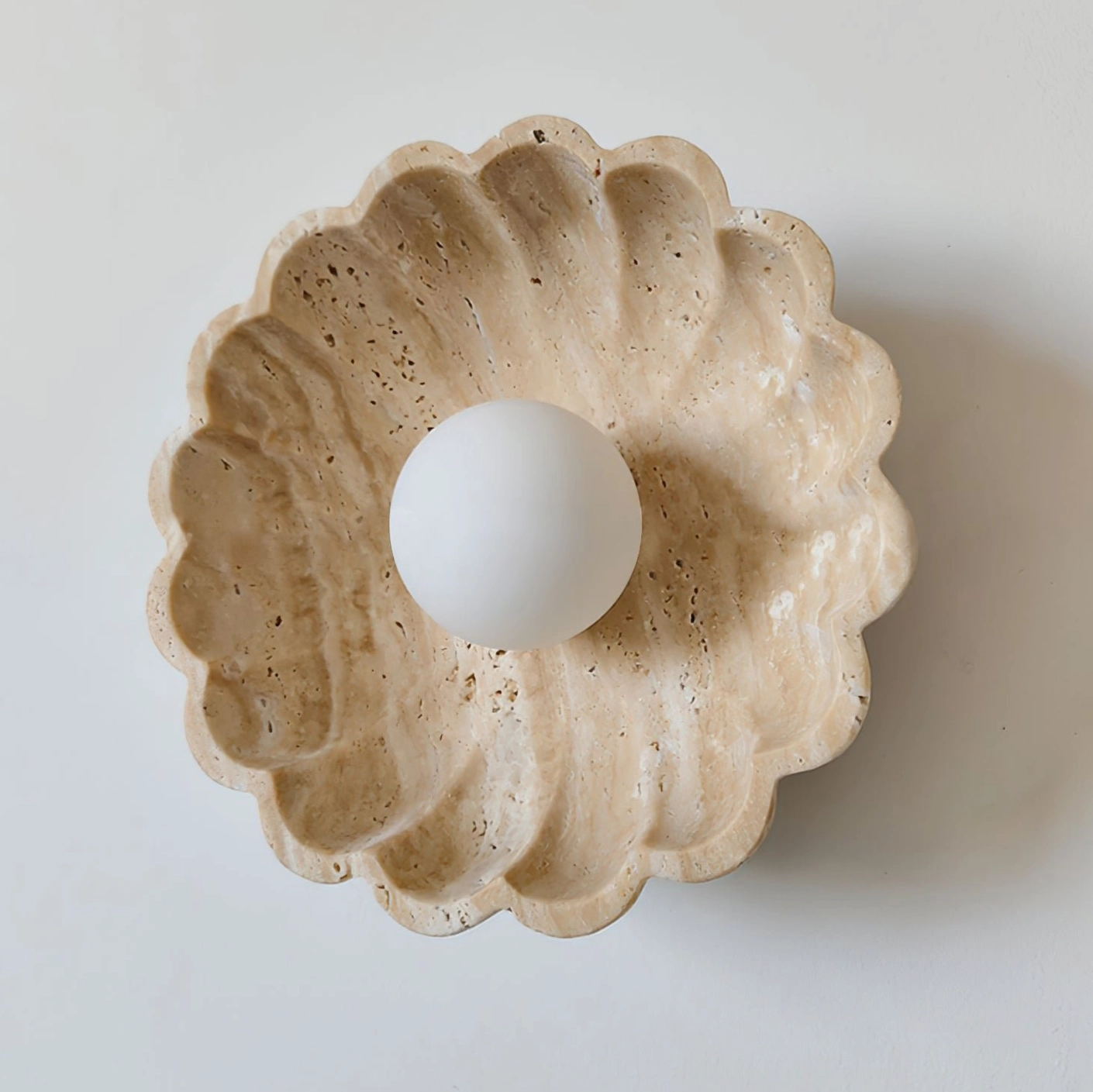Mid-century modern scalloped travertine wall lamp showcasing natural stone pores and texture detail