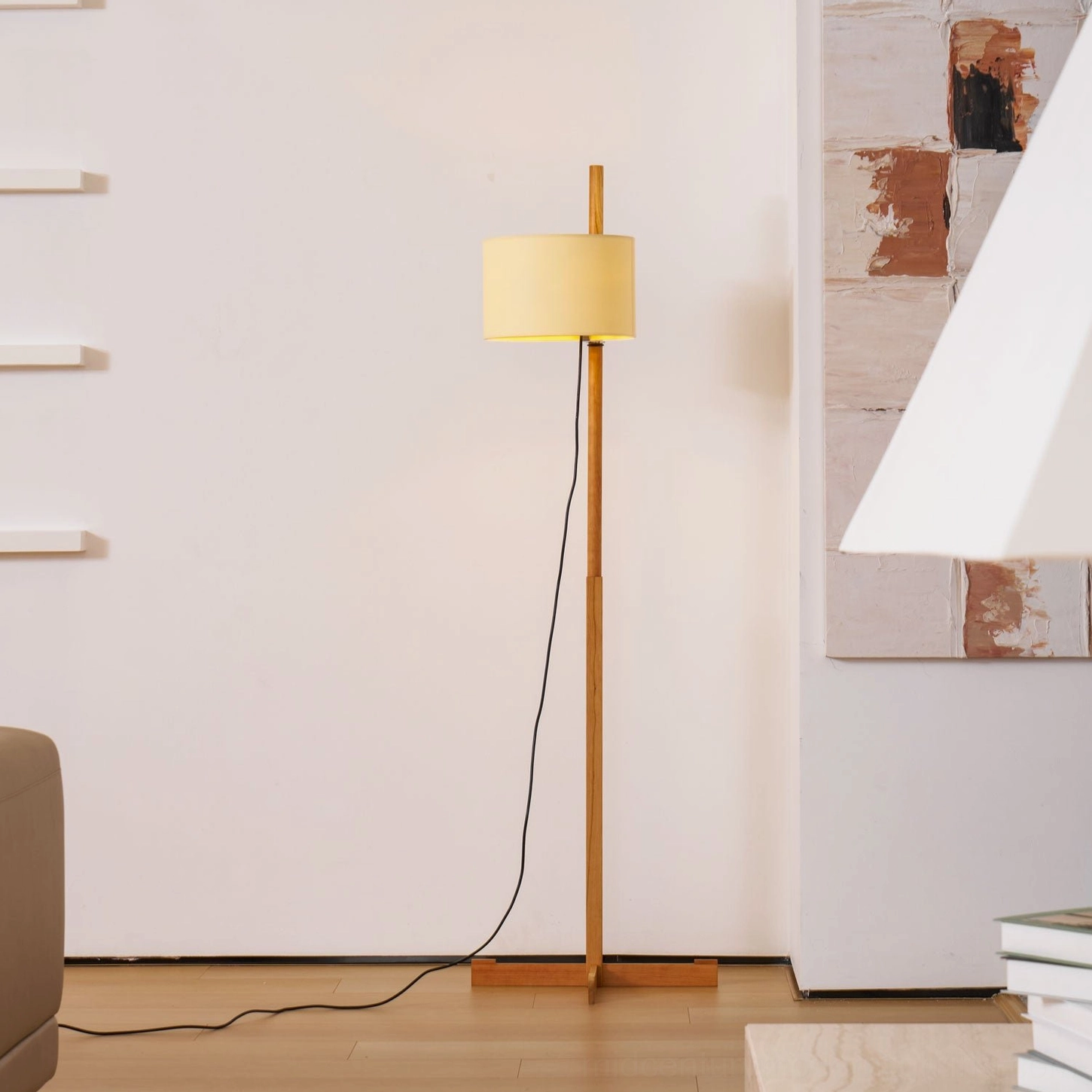Full length wooden floor lamp in empty modern living room with visible black power cord