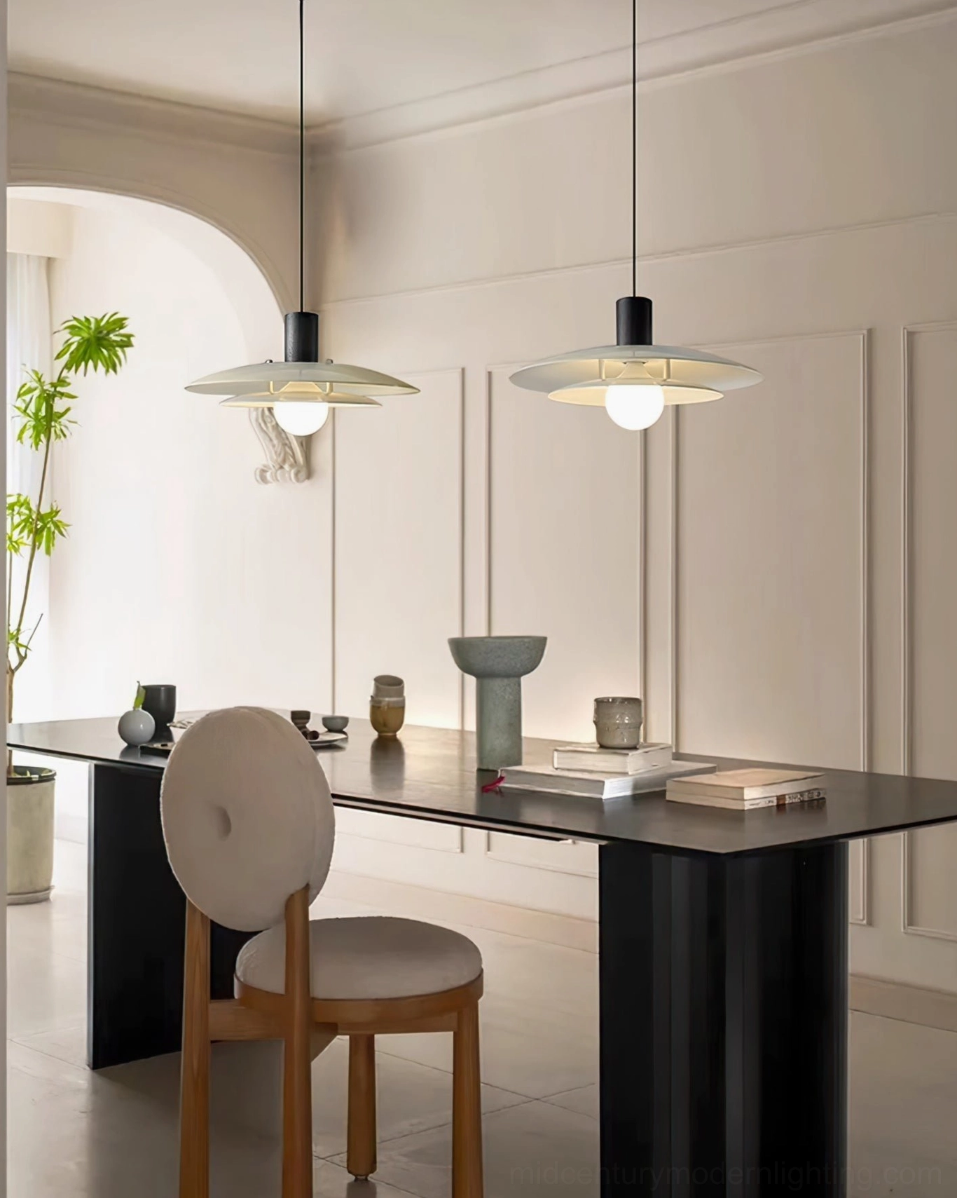Pair of Scandinavian pendant lights hanging above formal black dining table in minimalist home setting