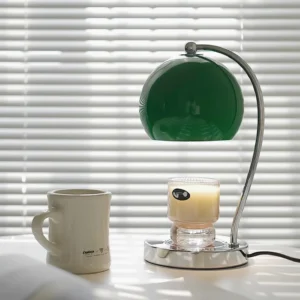 Candle warmer table lamp with off-white shade styled on minimalist tabletop with ceramic mug and window blinds
