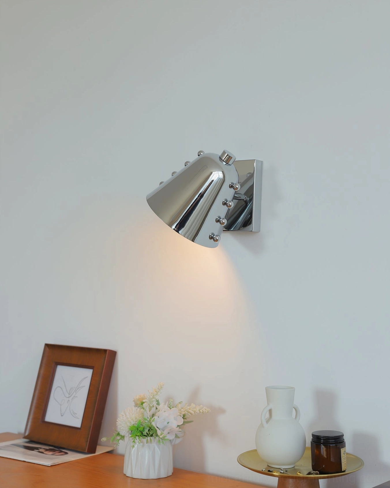 Wall sconce mounted above contemporary accent table with styling objects and fresh flowers
