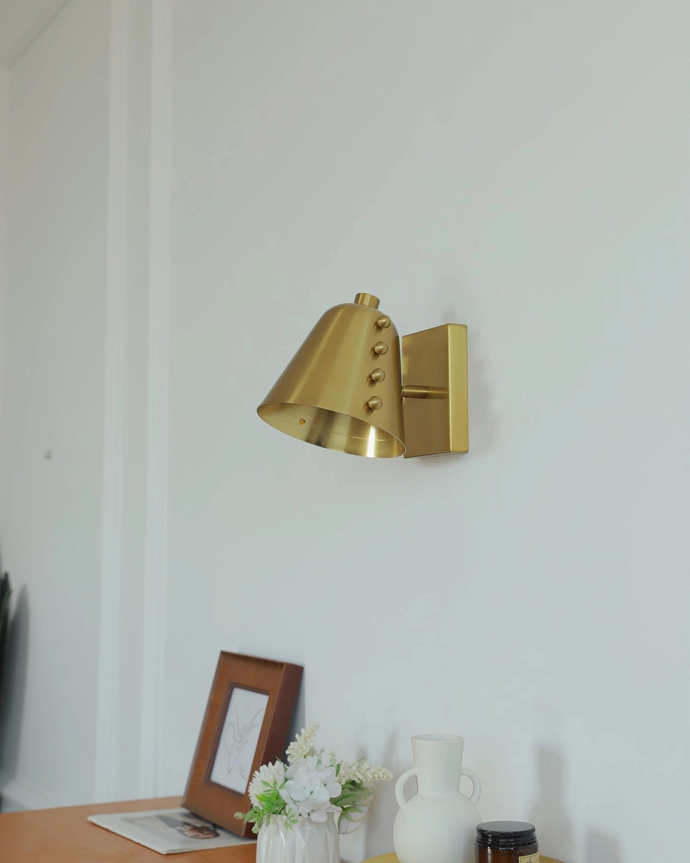 Wall sconce at night showing illuminated cone shade with warm light distribution