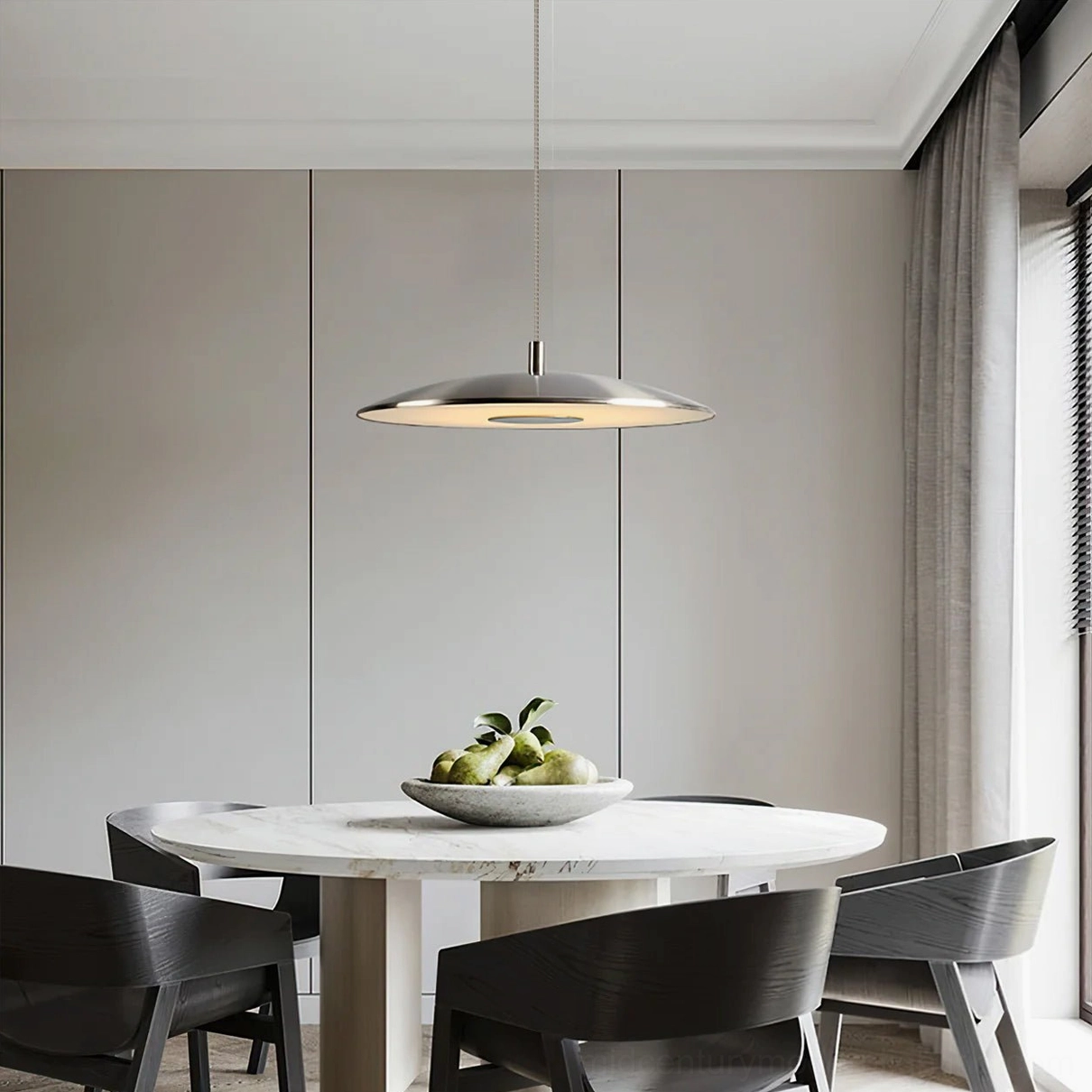Silver scope pendant above round dining table with modern minimalist dark accent chairs