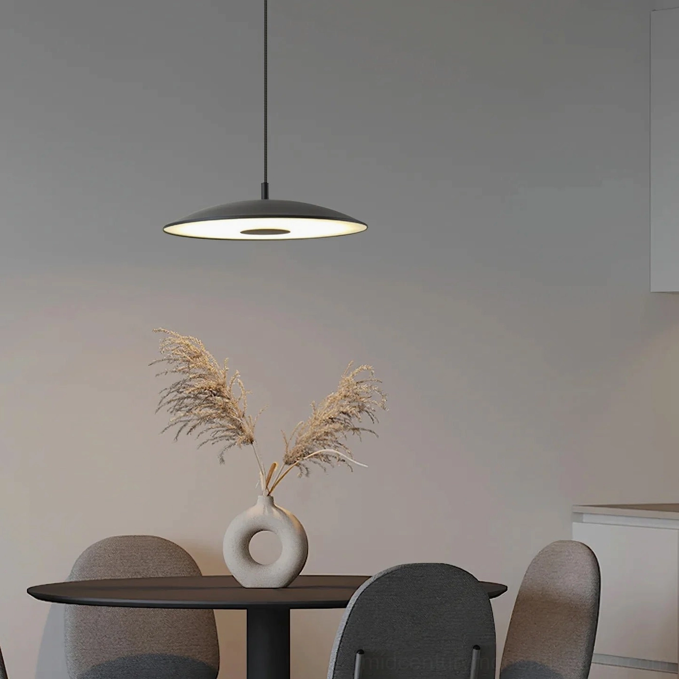 Black disc pendant lamp in modern dining space with warm minimalist decor