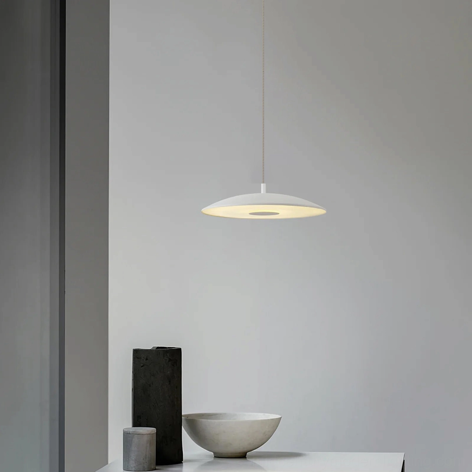 White scope pendant light in minimalist dining corner with clean modern finish