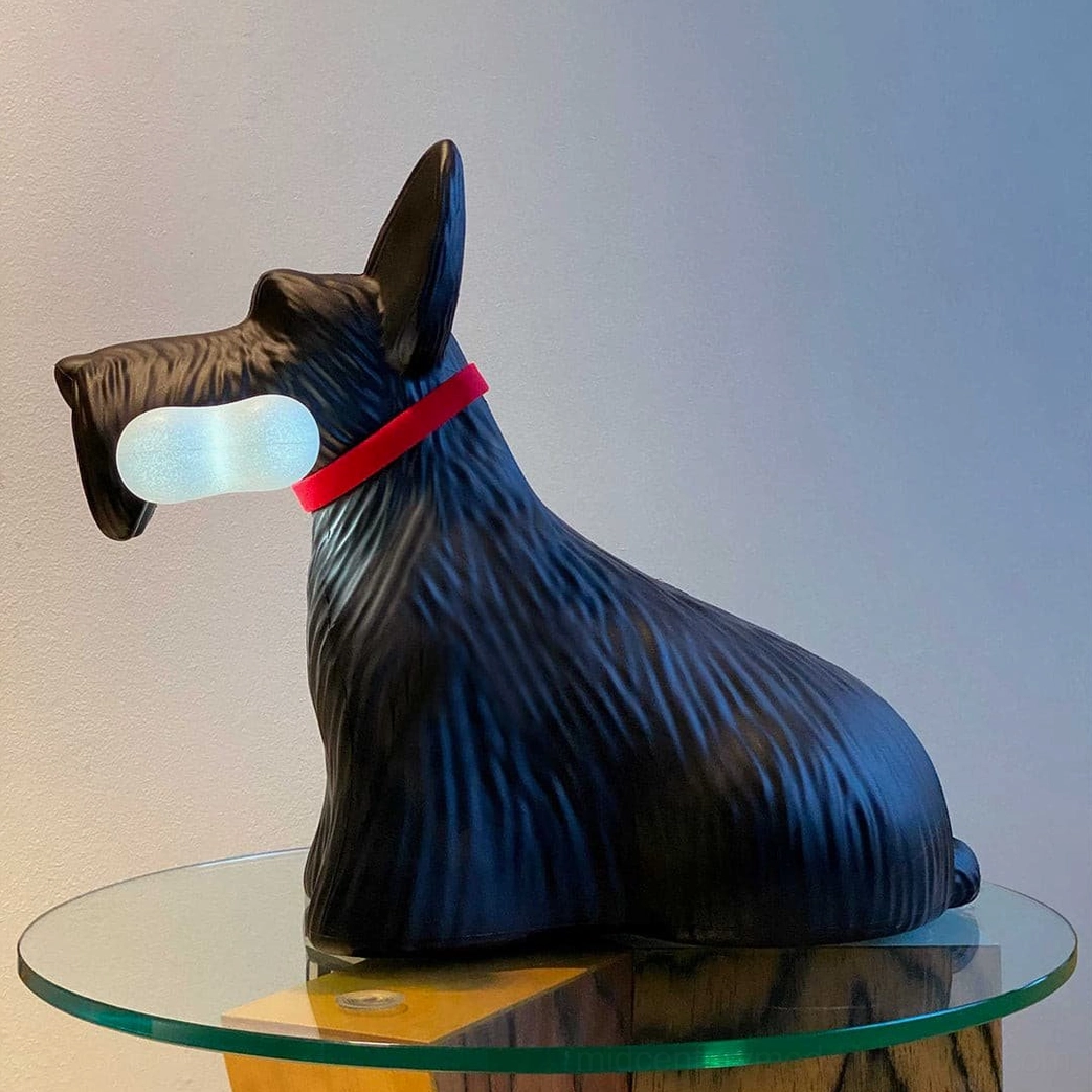 Black Scottie terrier table lamp with textured matte finish and red collar, side profile on glass top side table