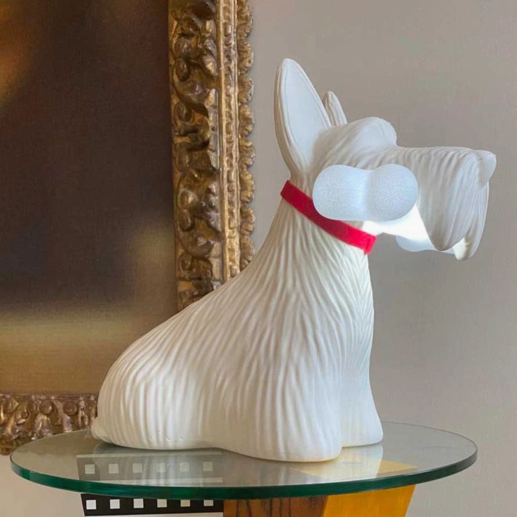 White Scottie dog table lamp with red collar and illuminated bone, rear-side view on ornate gold wall decor background