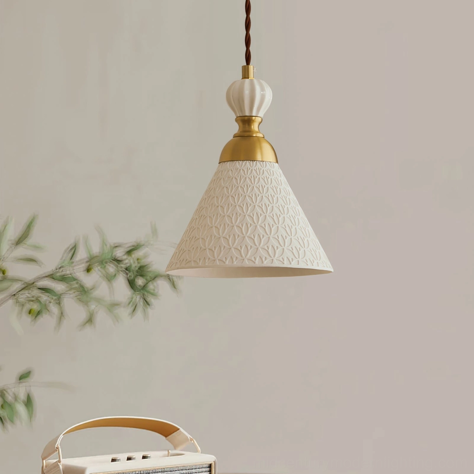Modern ceramic pendant light with tapered textured shade and brass accents displayed indoors with green foliage