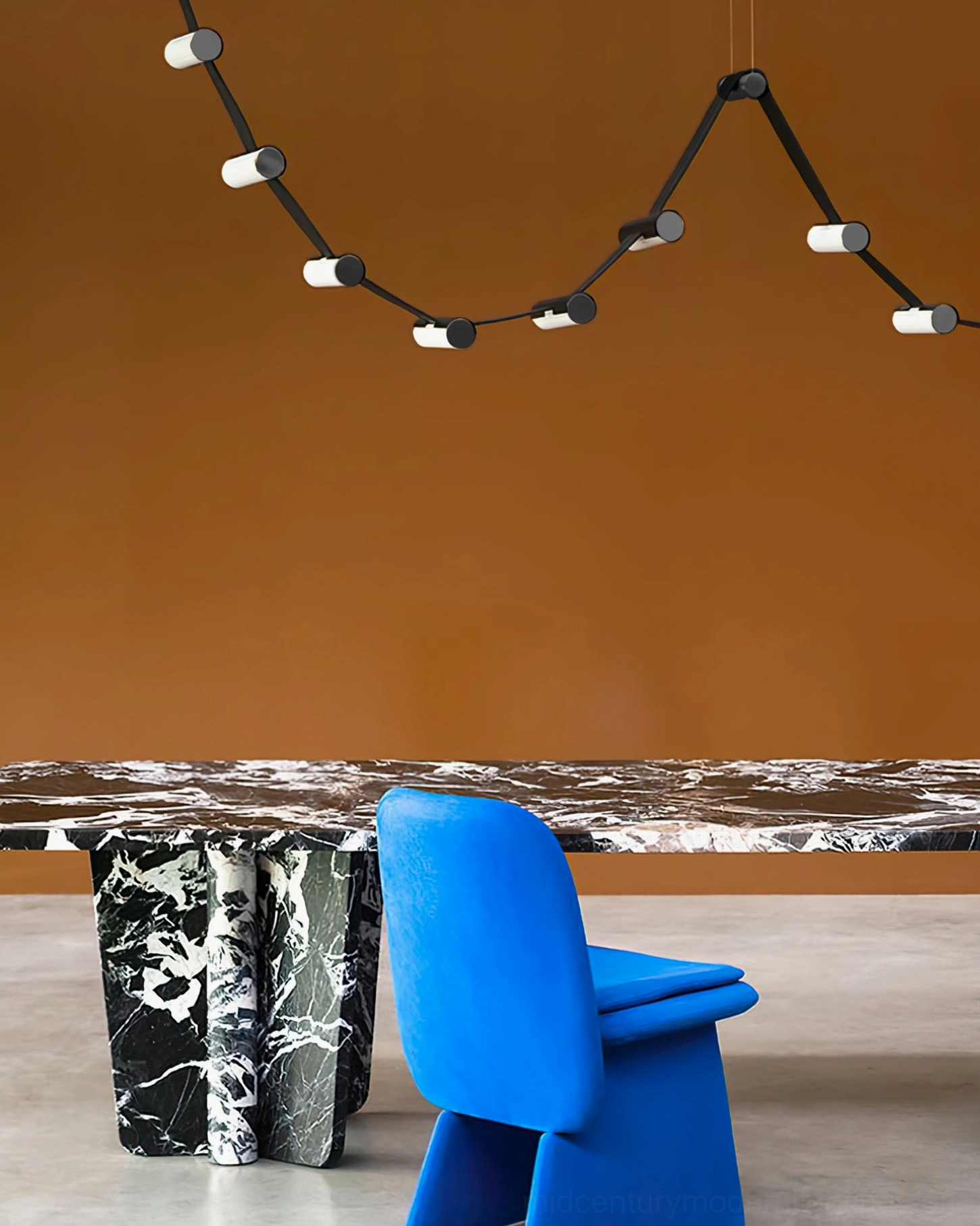 Compact curved black metal chandelier in elegant dining room with terracotta accent wall, sculptural LED lighting