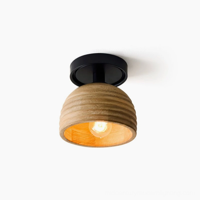 Front low-angle view of sculptural ribbed wood ceiling light with glowing warm yellow filament bulb against white backdrop