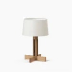Sculptural wooden table lamp with cross base and white linen shade, front view studio shot