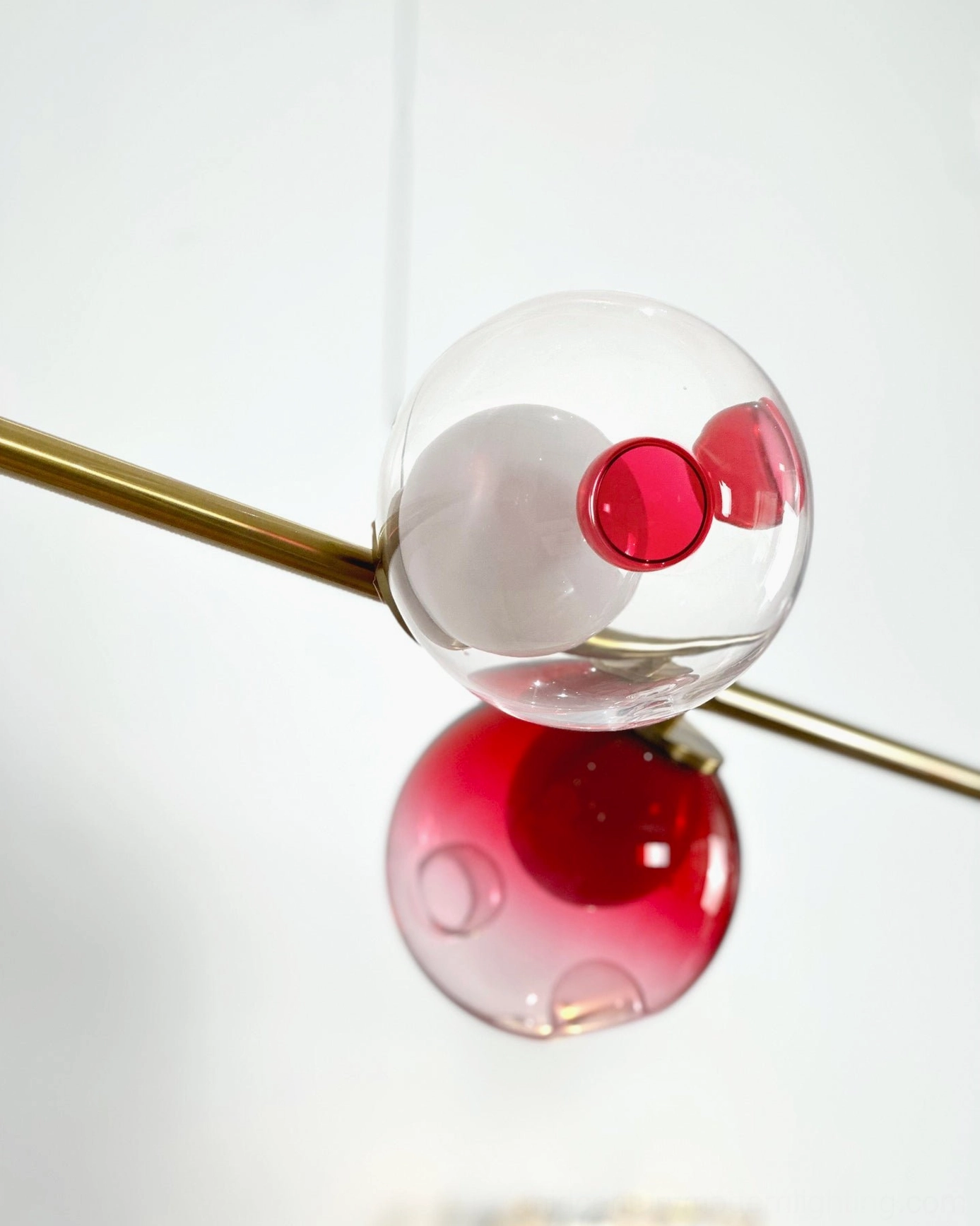 Sedna six-light linear chandelier side profile showing elegant brass rod framework and suspended glass orb arrangement
