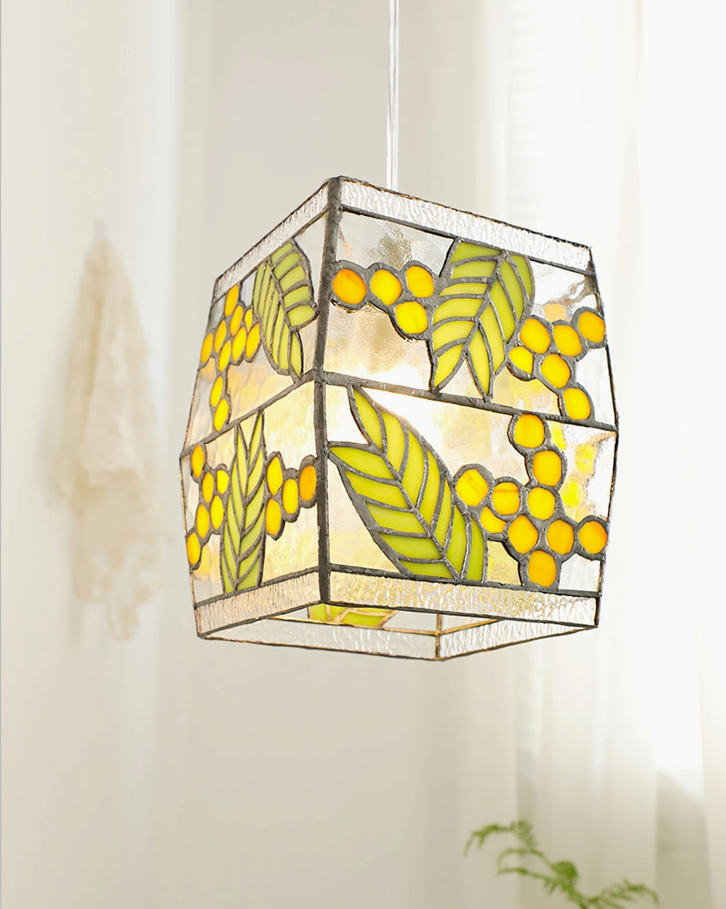 Low-angle view of stained glass cube pendant light showing textured glass panels and botanical leaf design details