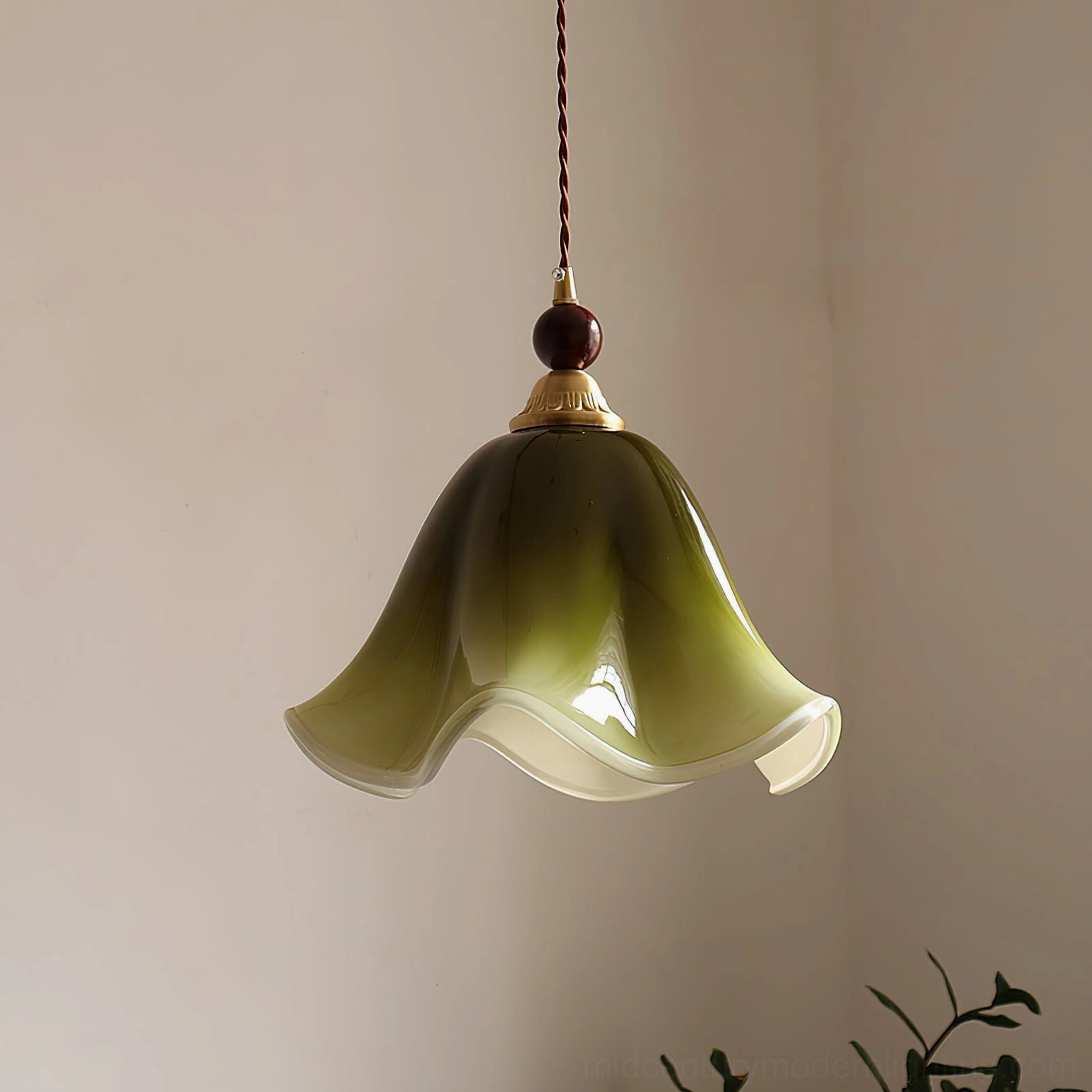 Green gradient Selene pendant light hanging in minimalist interior corner with twisted brown fabric cord and walnut wood accents