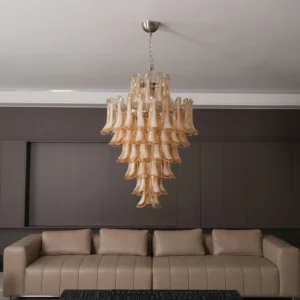 Illuminated Murano glass chandelier casting warm amber glow in modern dark wood living room with beige sectional