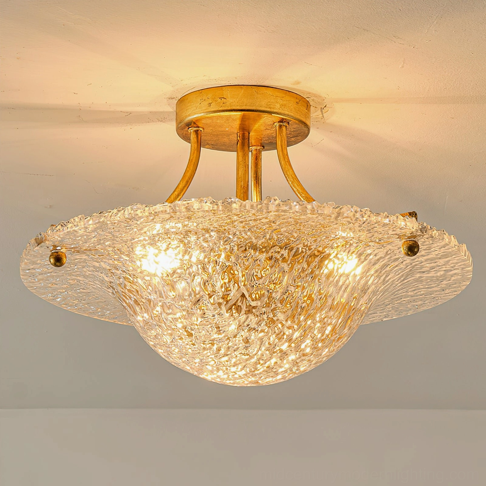 Serilda ceiling mounted fixture with brass gold finish and illuminated clear textured glass, low-angle view in residential setting