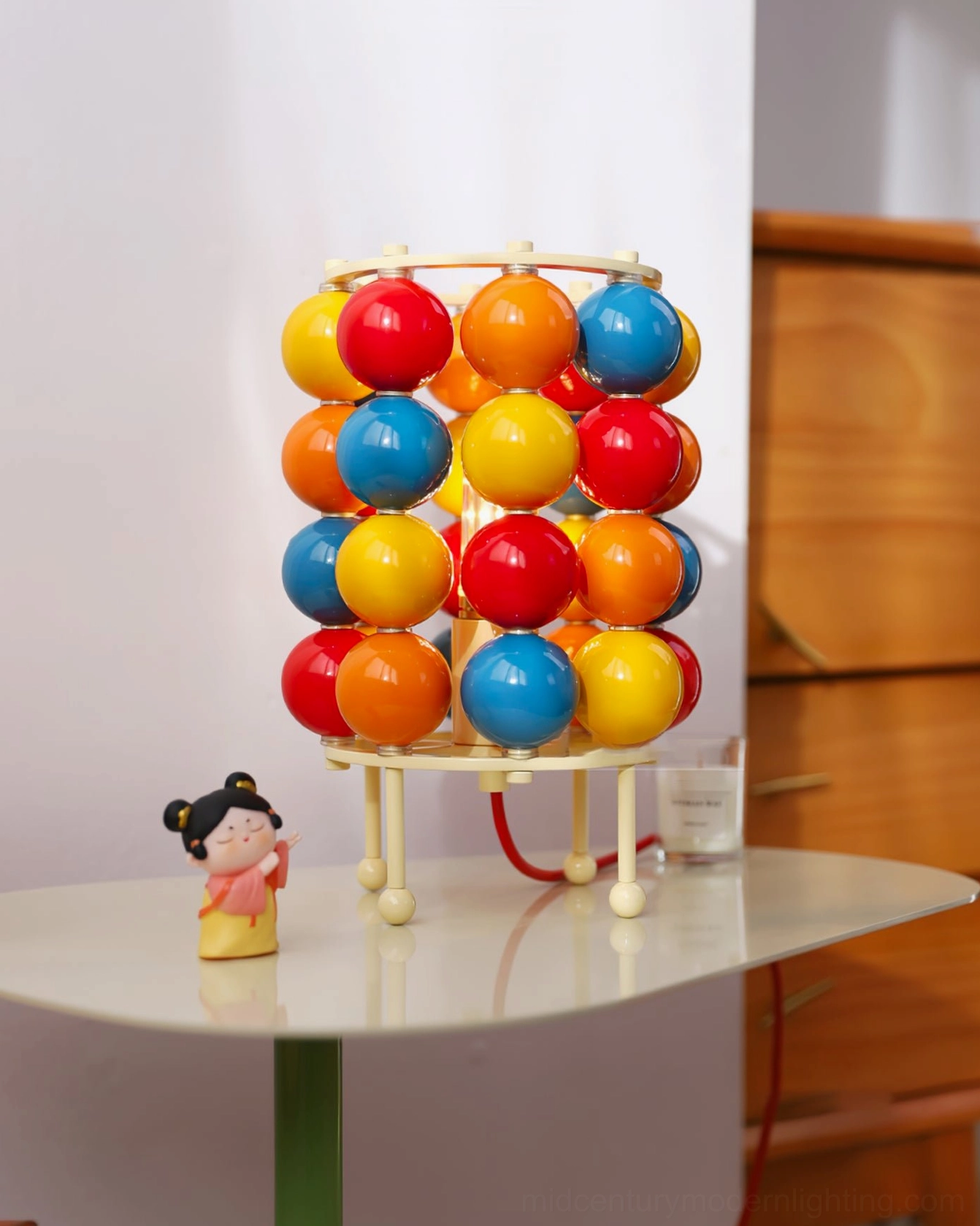 Low-angle close-up of Sfera ball lamp with red cord and wooden tabletop surface
