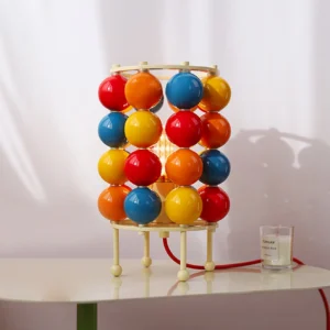 Modern Sfera ball table lamp on white side table with red power cord and decorative candle