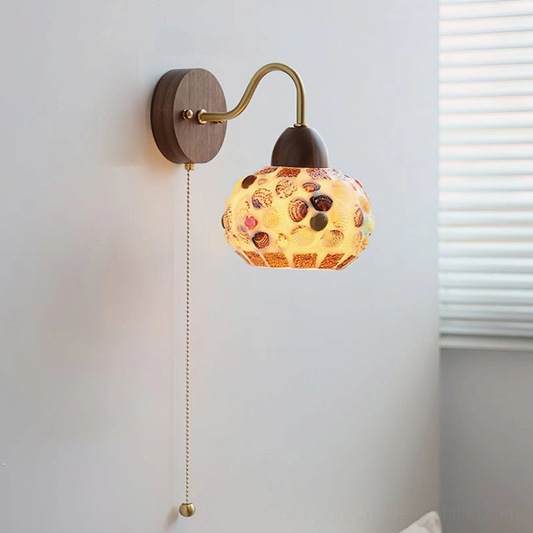 Shell pattern embossed wall lamp with marine-inspired glass shade and brass pull chain - side view on wall display