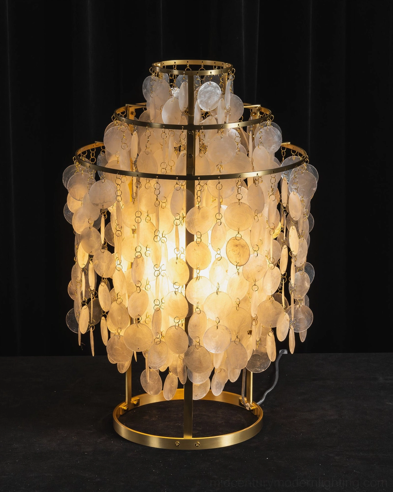 Luxury vintage capiz shell table lamp illuminated with warm light on dark backdrop
