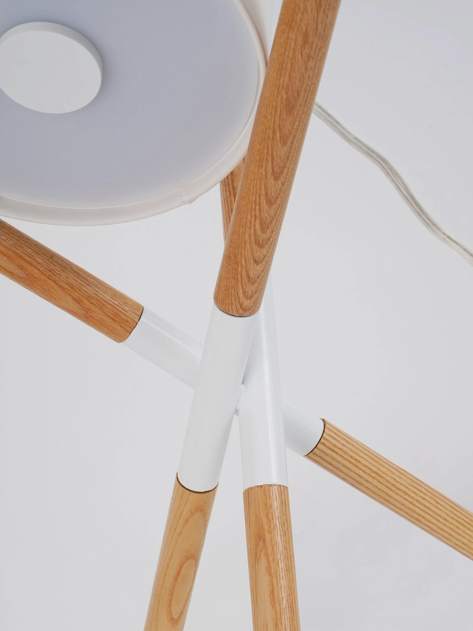 Close-up low-angle view of mid-century modern tripod lamp white cross connector and natural wooden legs