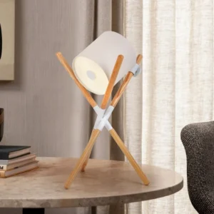 Mid-century modern tripod table lamp with light wood stand and illuminated white shade on marble side table in luxury living room