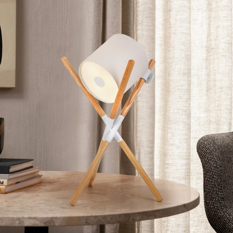 Mid-century modern tripod table lamp with light wood stand and illuminated white shade on marble side table in luxury living room