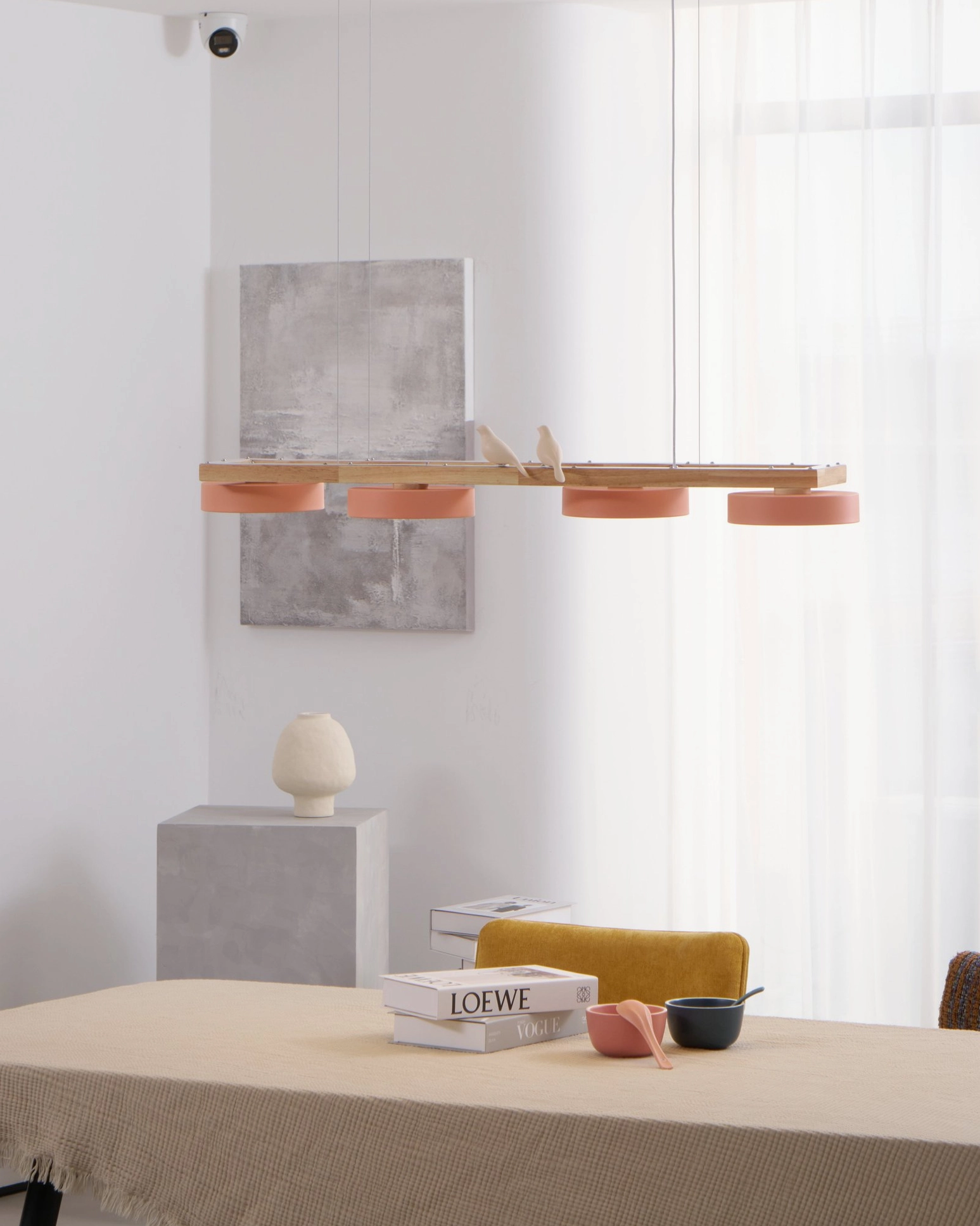 Pink-shaded Sienna Bird Chandelier with natural wood frame in bright minimalist dining room