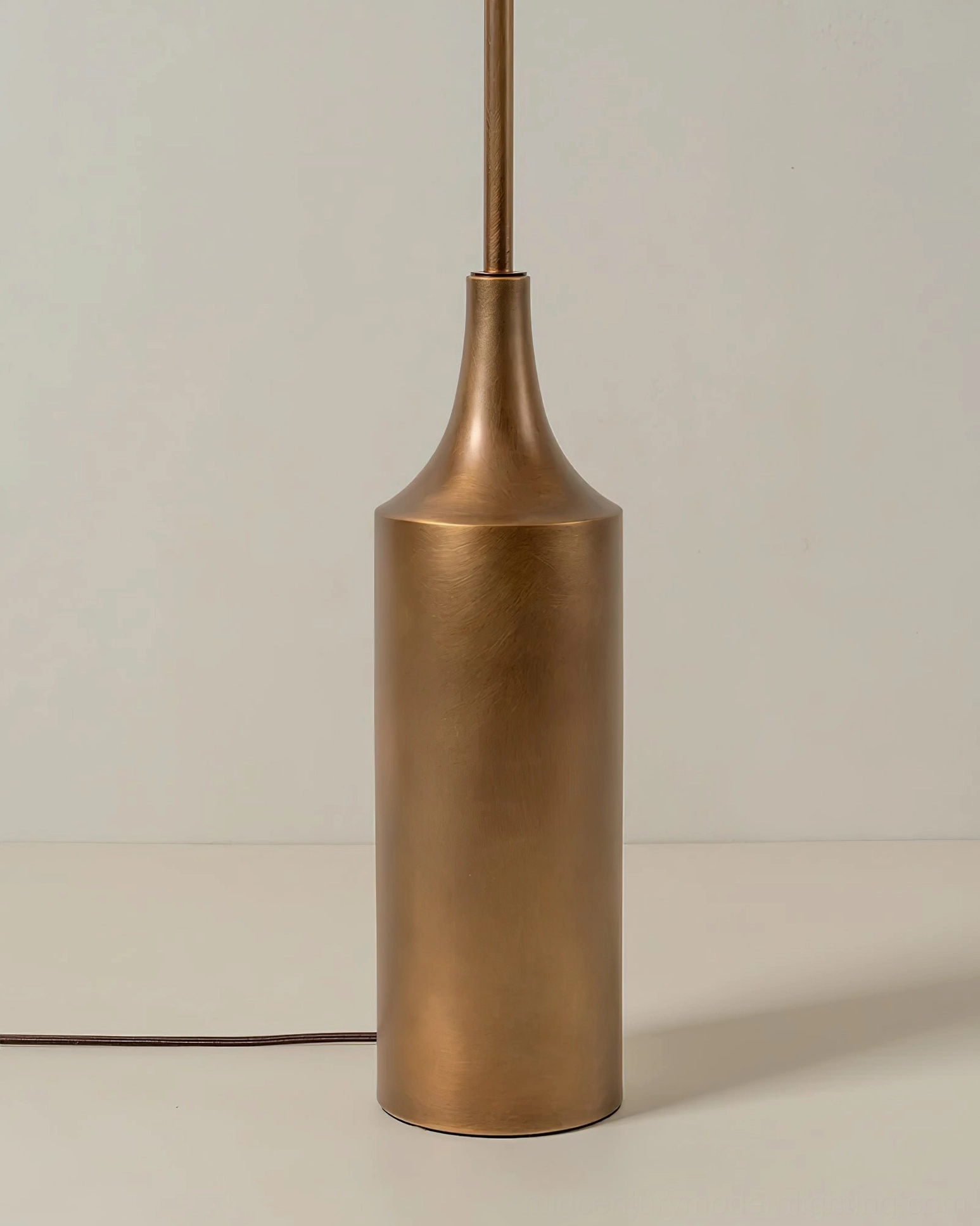 Sierra floor lamp base and pole detail, close-up front view, showcasing the cylindrical matte gold cast metal base and smooth tapered metal stem