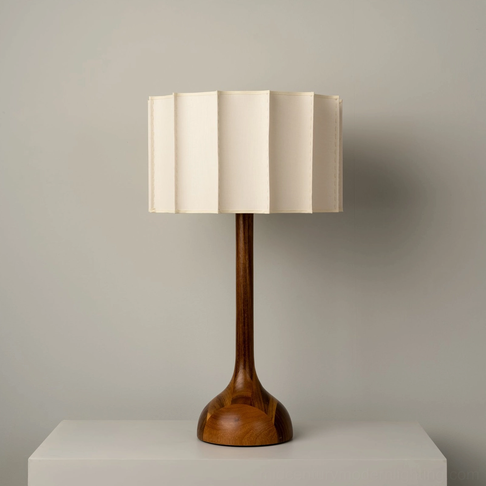 Sierra table lamp featuring sculptural turned walnut wood base and clean silhouette on minimalist white platform