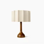 Sierra mid-century modern table lamp with solid walnut turned wooden base and pleated beige fabric shade, studio front view