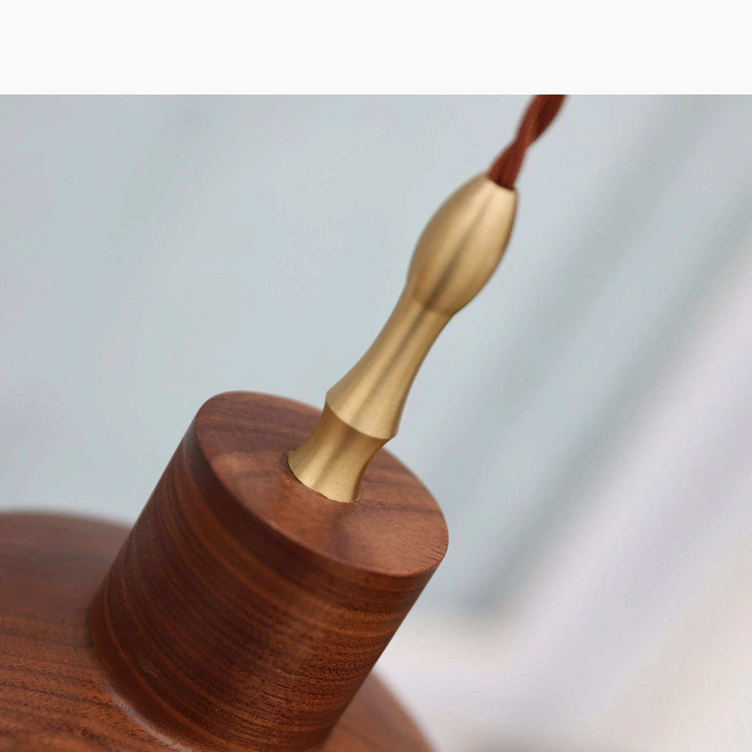 Close-up detail of silas pendant hardware showing polished brass stem connector where it meets solid walnut dome base
