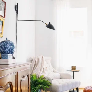 Single-arm swing sconce in matte black mounted in vintage modern living room above sitting area