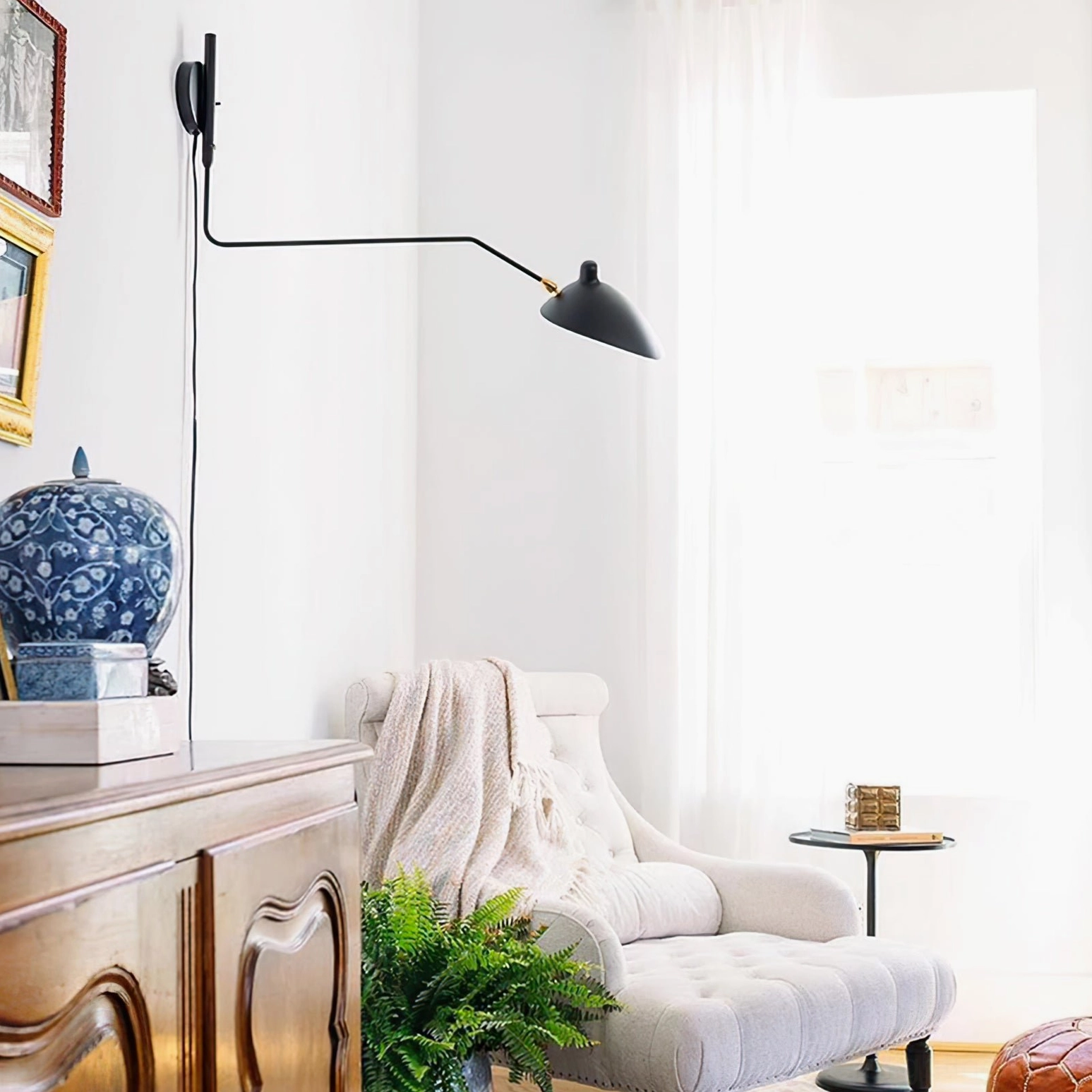 Single-arm swing sconce in matte black mounted in vintage modern living room above sitting area