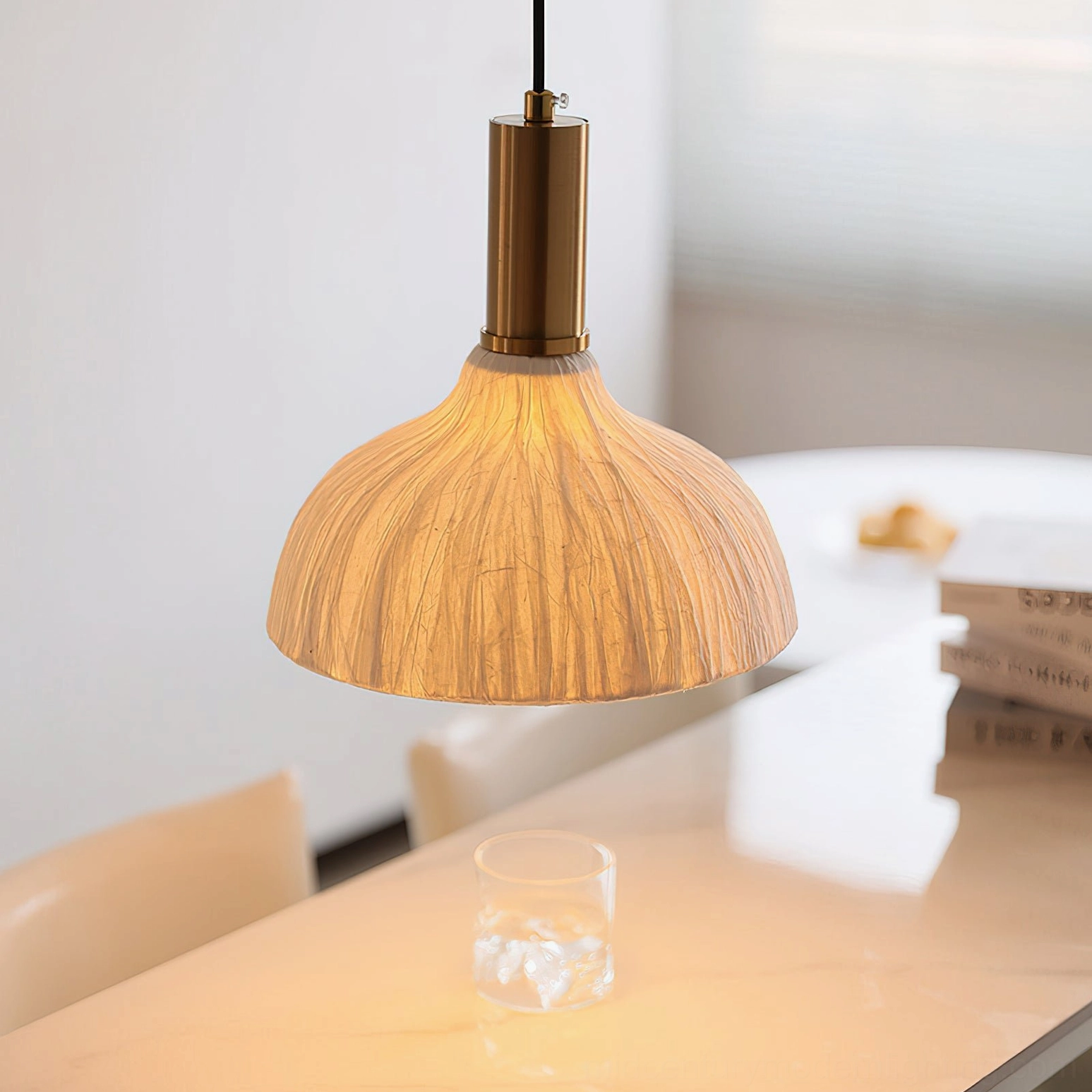 Dome-shaped Siya pendant with ribbed light brown fabric shade and brass hardware over minimalist dining setup
