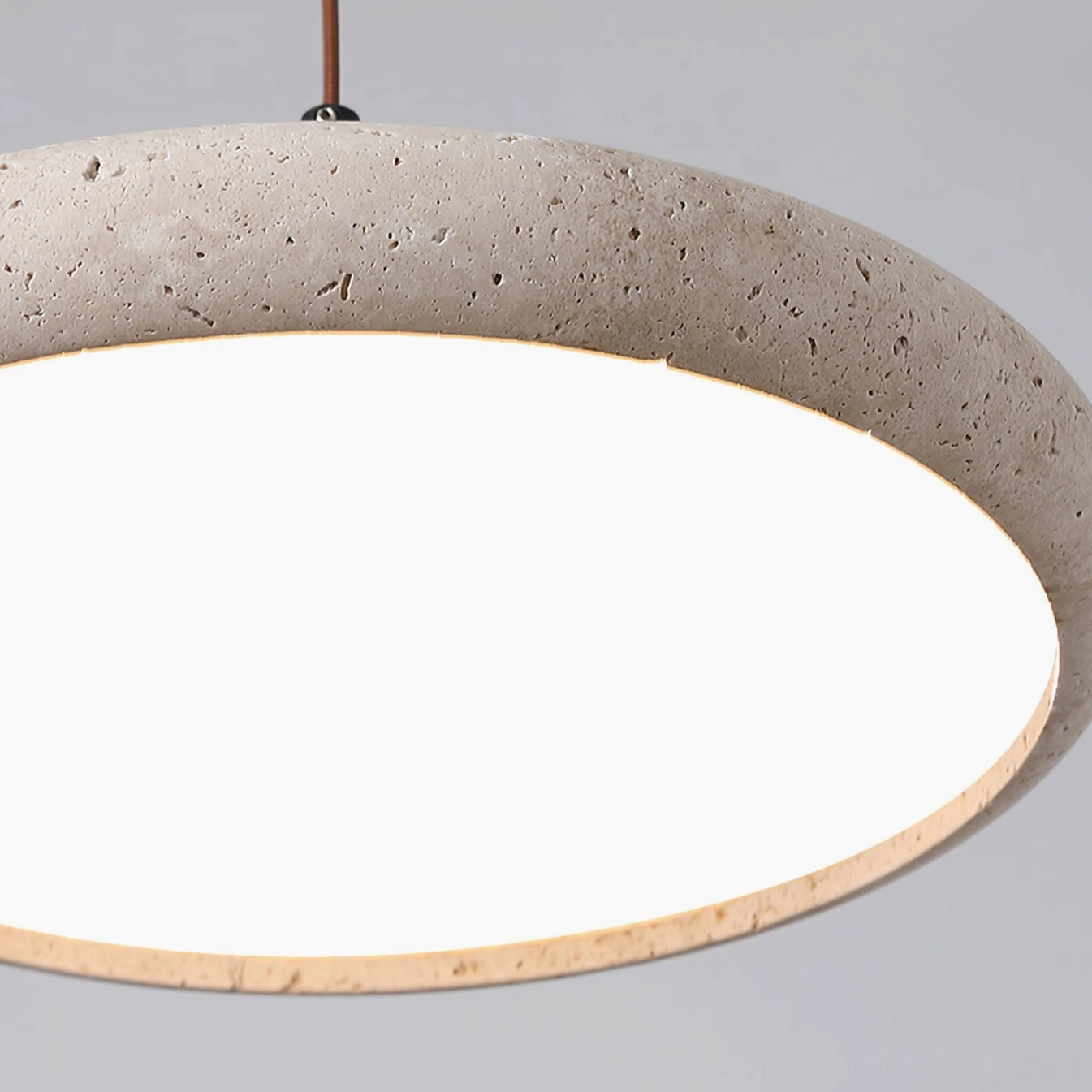 Detailed view of Siyane travertine pendant shade edge showing porous stone texture and warm LED light