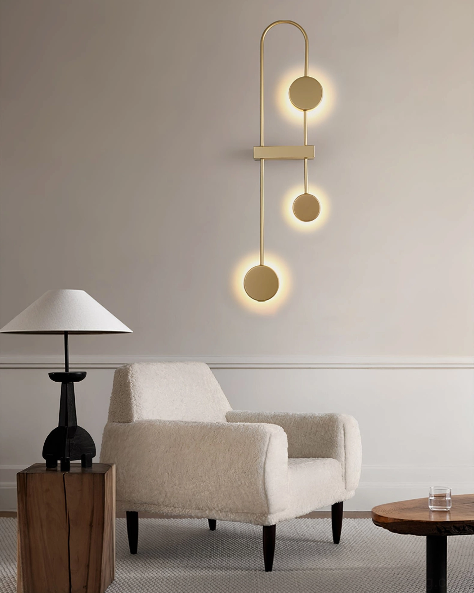 Slim brushed gold modern wall sconce with three circular metal pendants and warm ambient glow