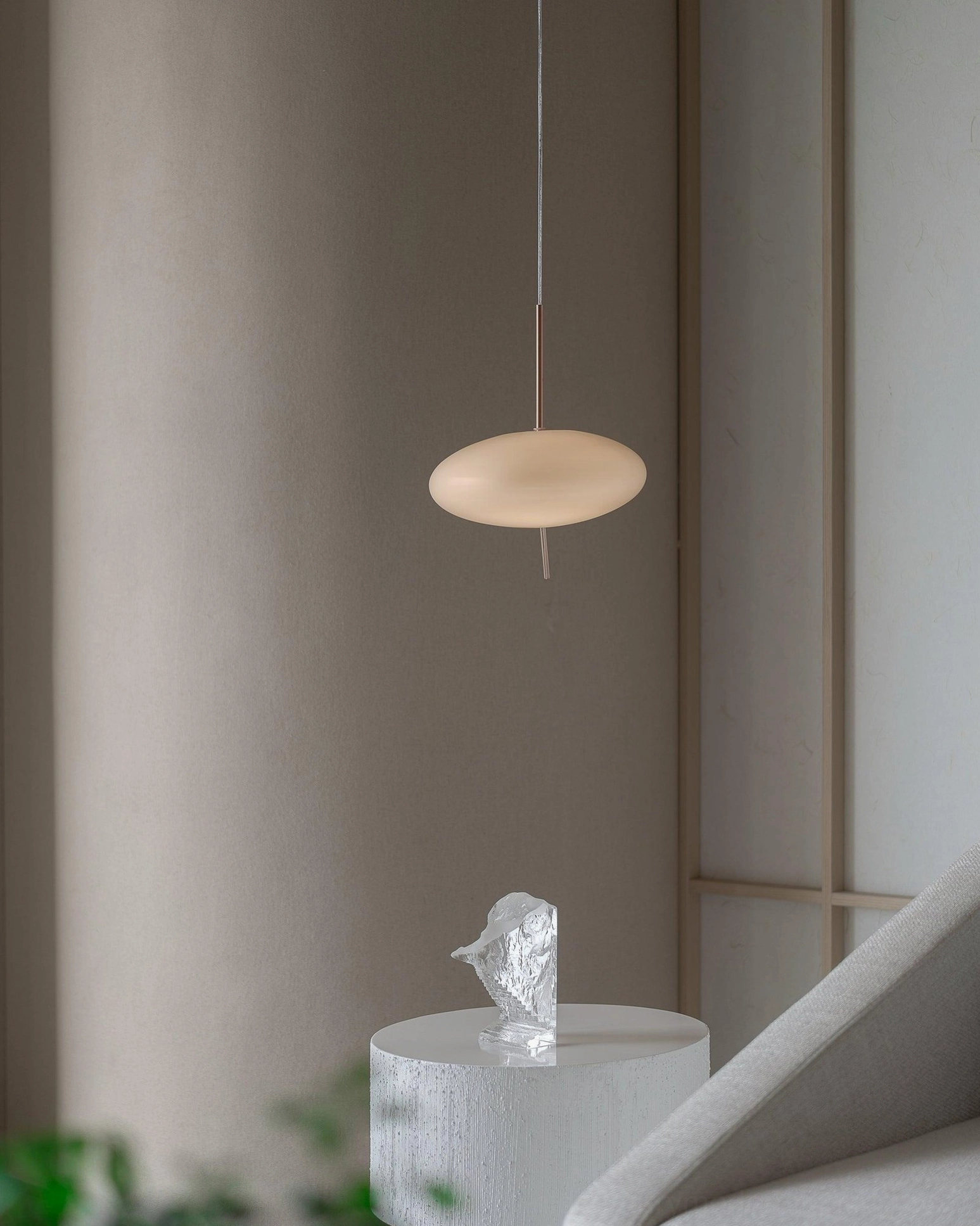 Small pebbles pendant light in minimalist interior corner with light tan acrylic shade, wabi-sabi aesthetic